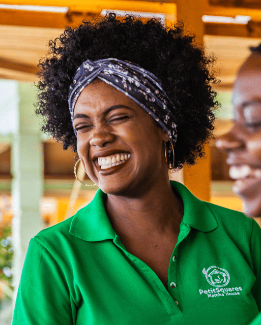 Woman wearing a green shirt with a logo, smiling outdoors.