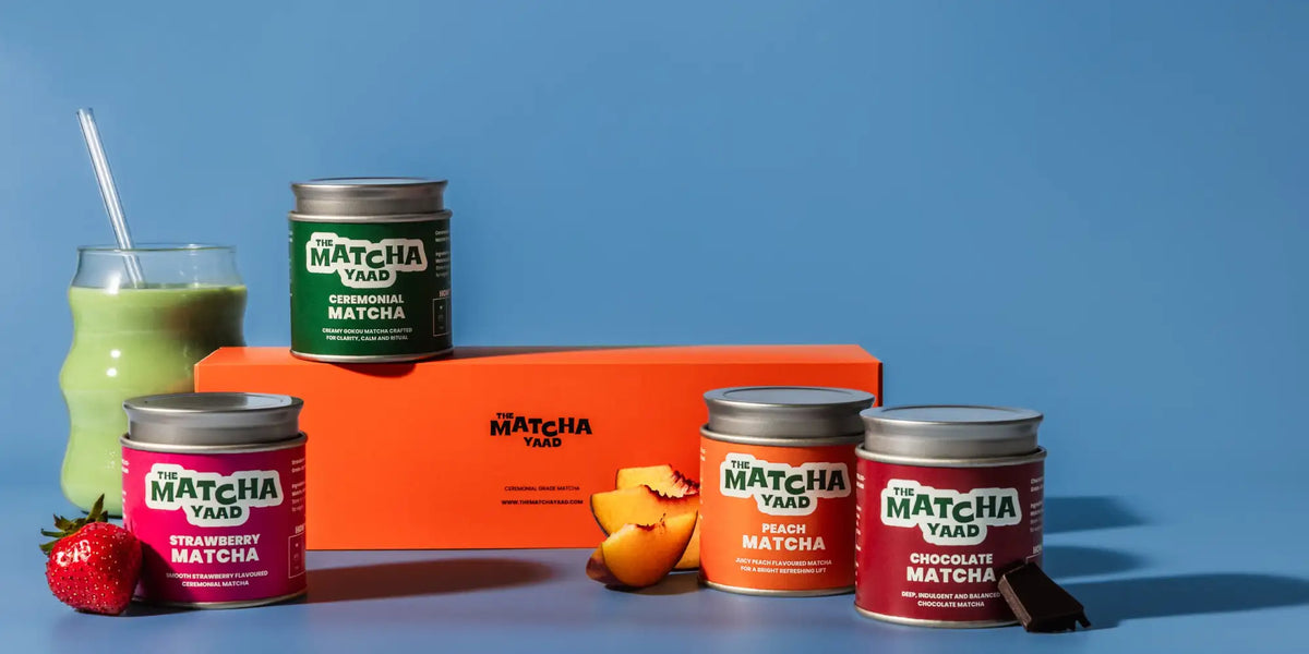 Orange rectangular box with ’the matcha yaad’ branding and matching matcha flavor jars arranged around it.