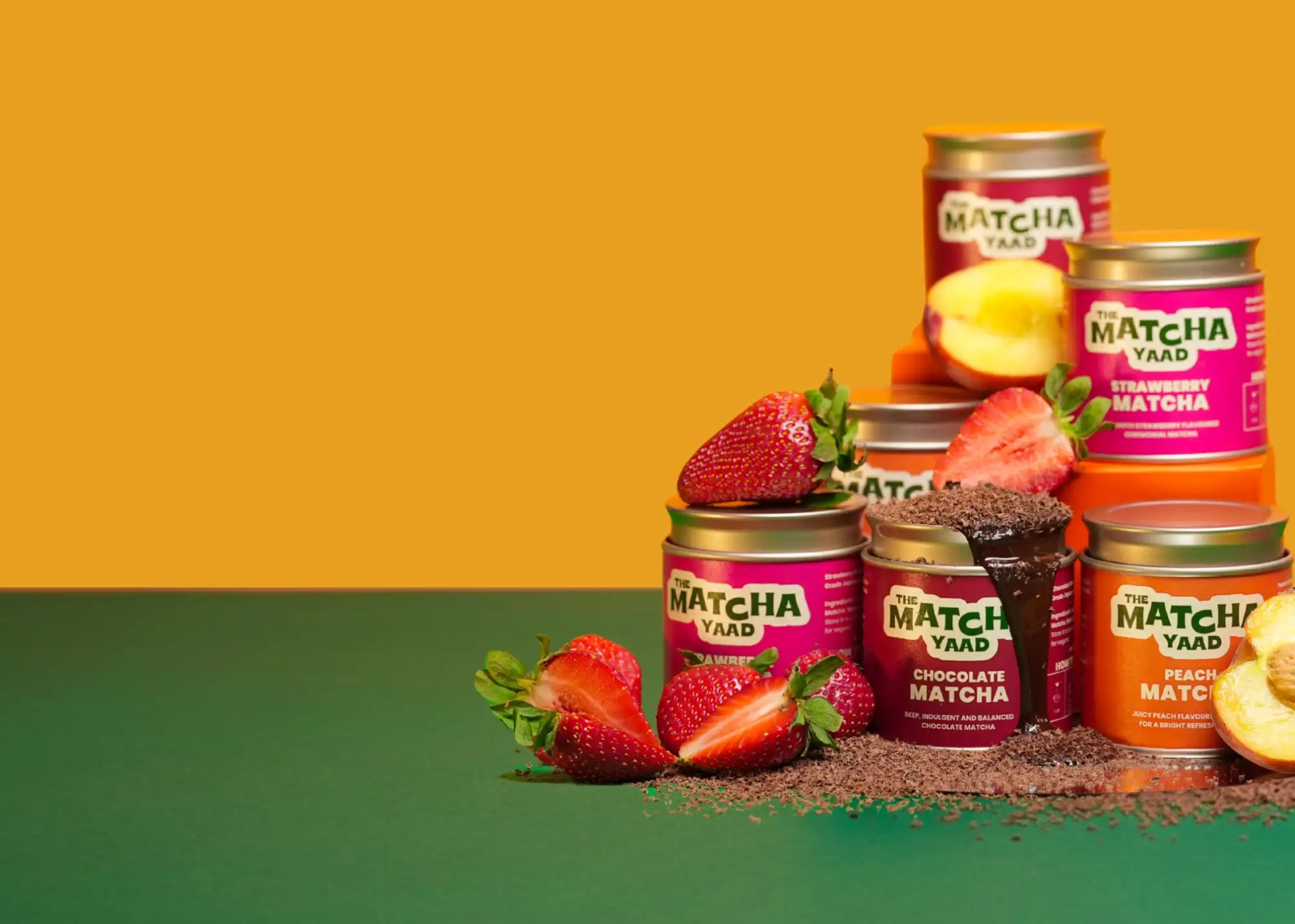 Pink and orange labeled jars of the matcha yaad matcha powder in various flavors, surrounded by fresh strawberries and peach slices.