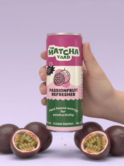 Hand holding Passionfruit Refresher drink can with whole and halved passionfruits, highlighting plant-based clean energy and no-jitter formula.